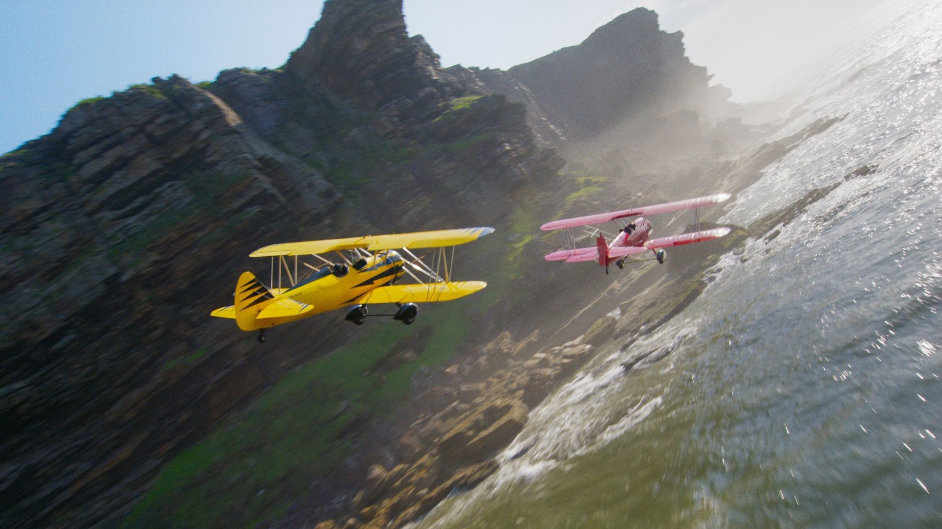 Yellow and red biplanes chasing each other.